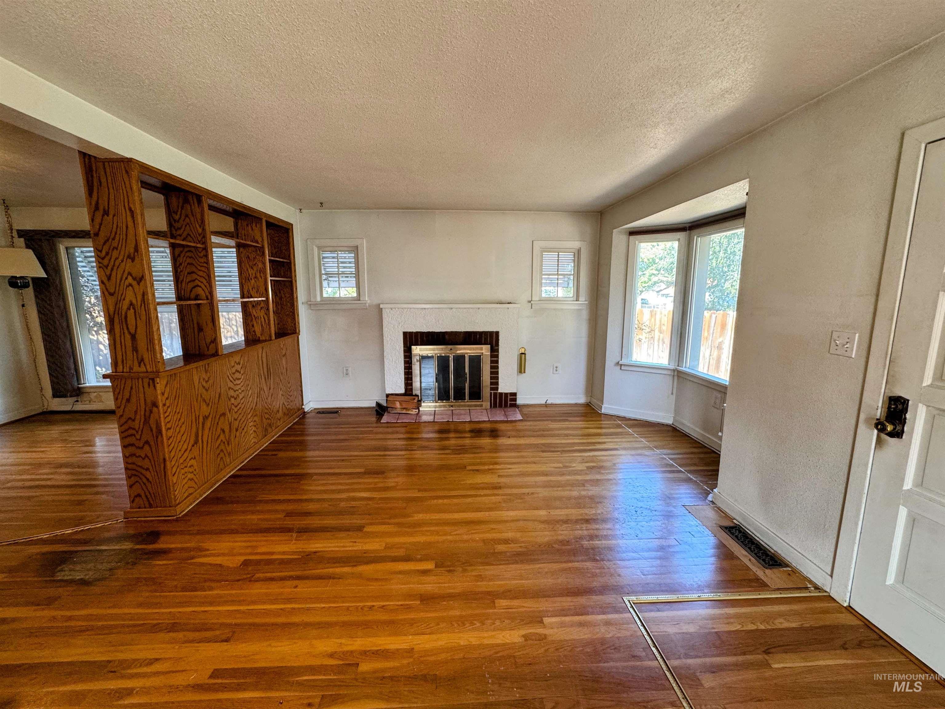 Unfurnished living room featuring wood finished floors, a textured ceiling, and a fireplace