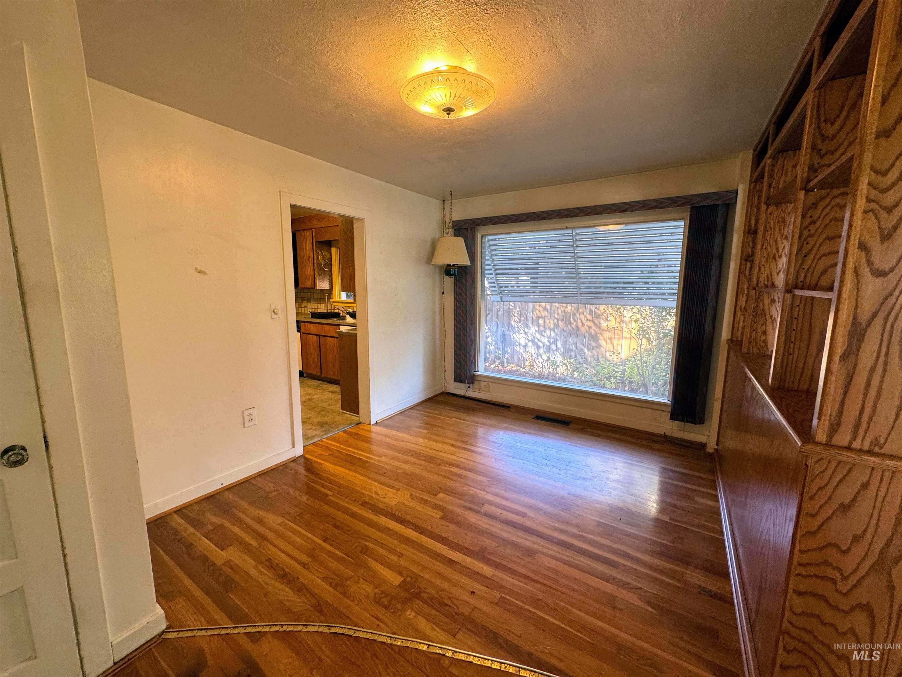 Unfurnished bedroom with a textured ceiling, wood finished floors, and ensuite bath