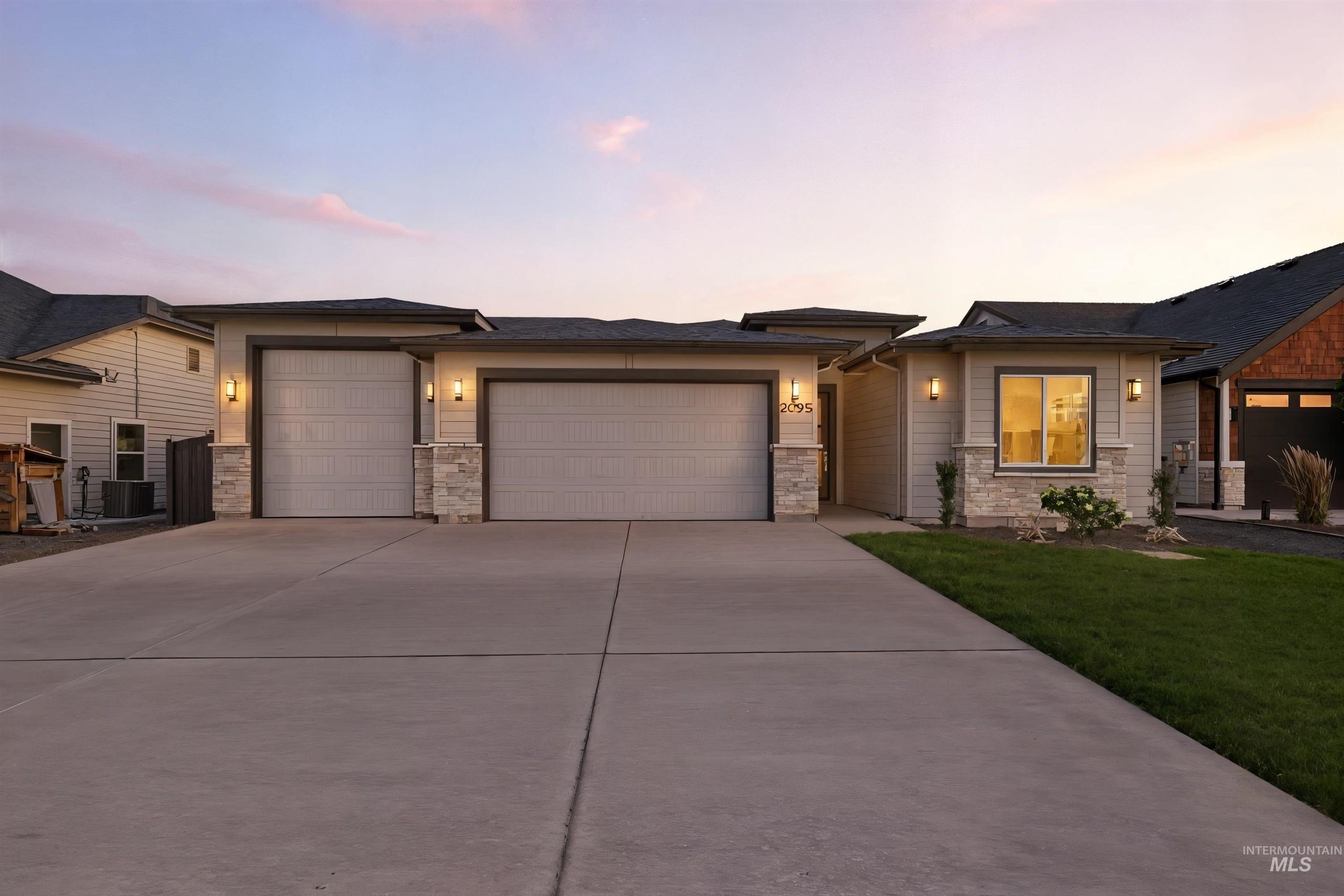 Prairie-style house with an attached garage, concrete driveway, and stone siding