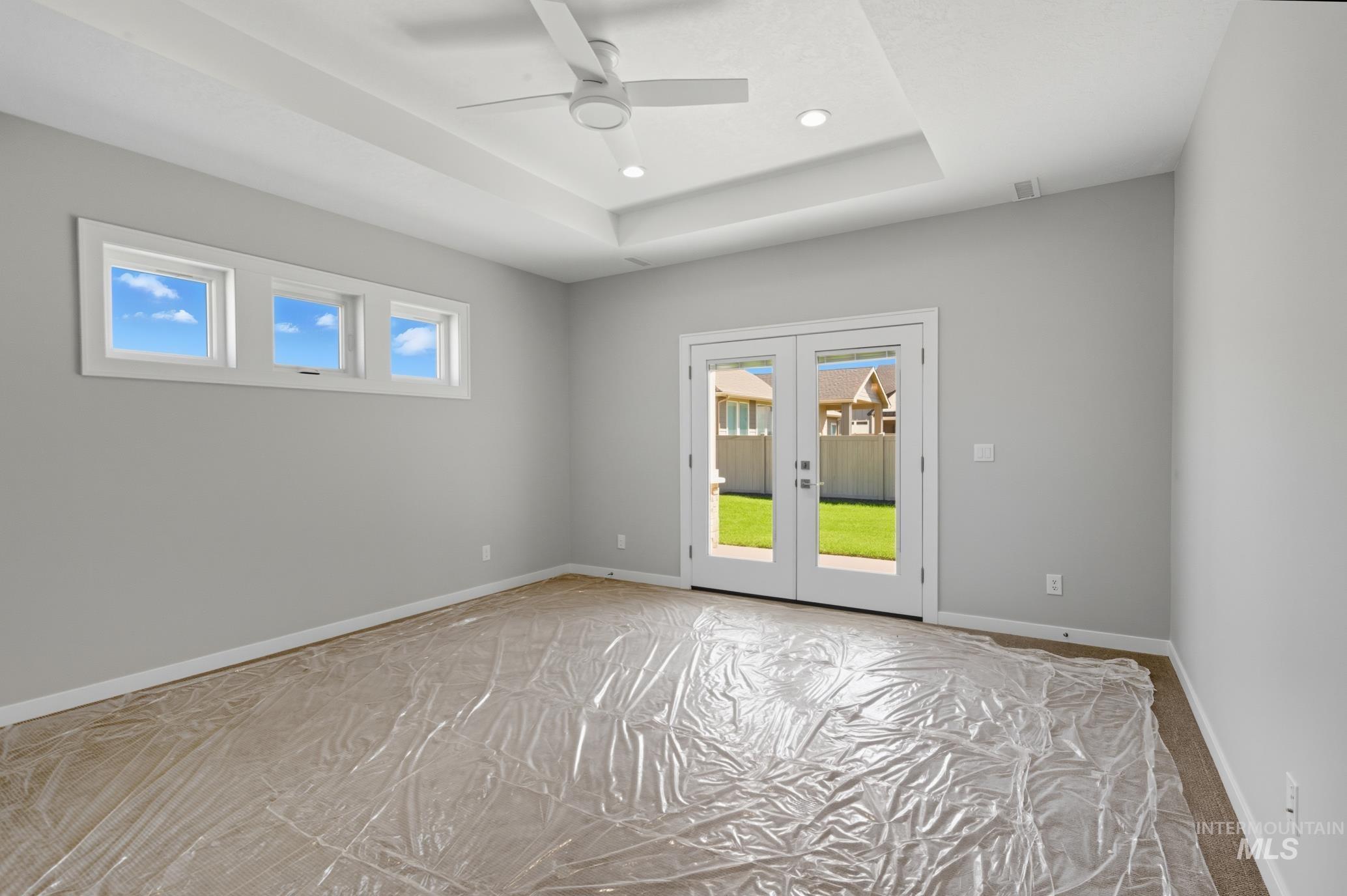 Empty room featuring french doors, a tray ceiling, a ceiling fan, and recessed lighting