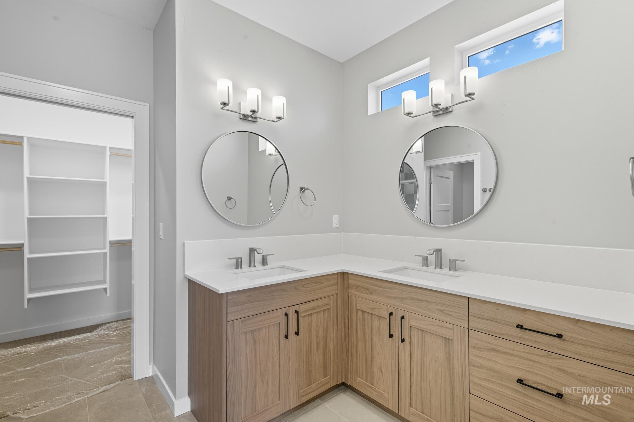 Full bath featuring a walk in closet and double vanity