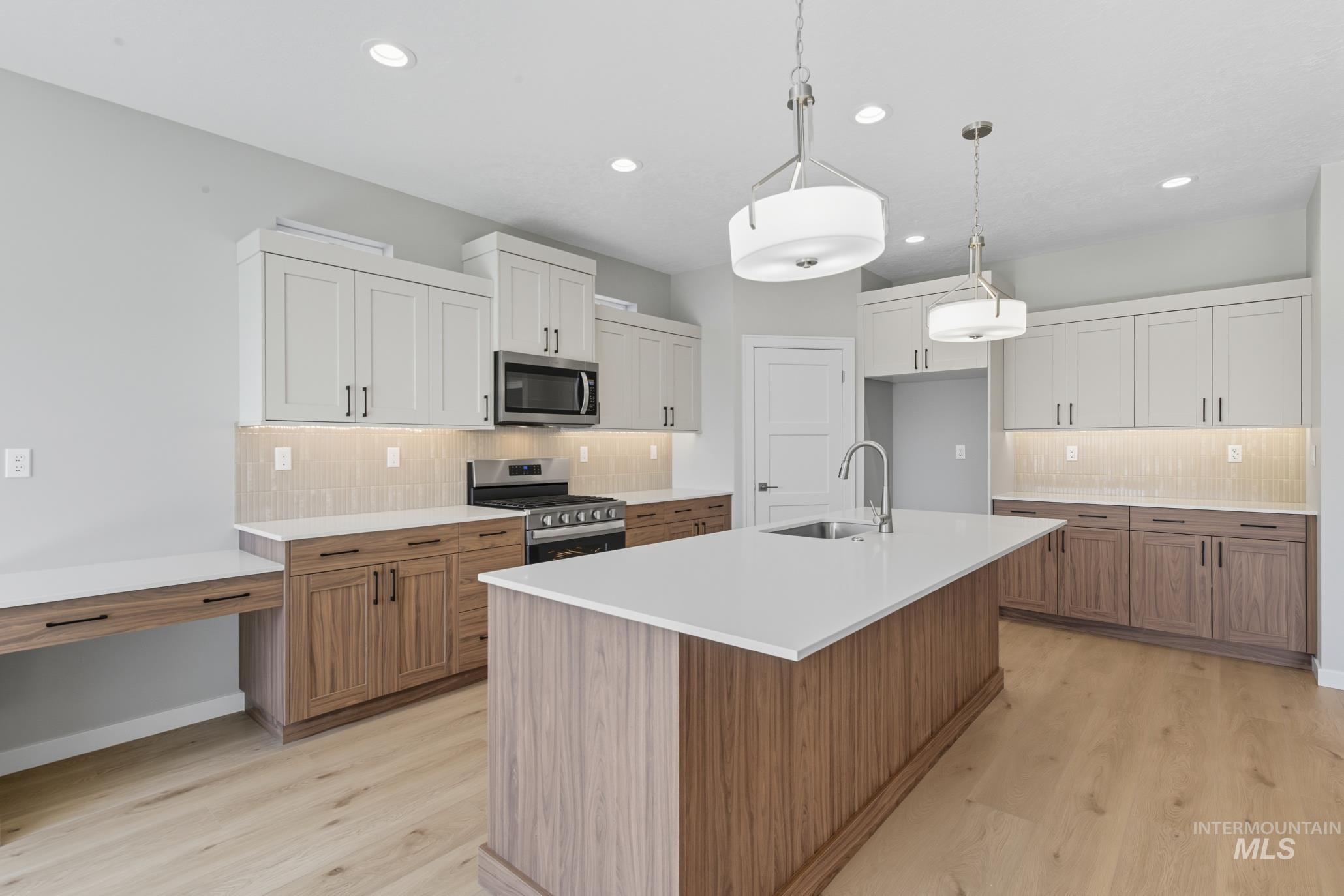 Kitchen with brown cabinetry, decorative backsplash, white cabinetry, appliances with stainless steel finishes, and recessed lighting