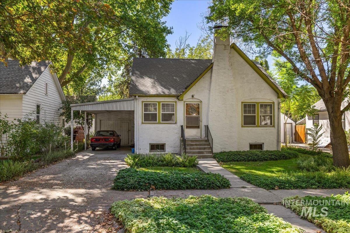 View of front of home featuring a chimney, driveway, stucco siding, a carport, and a shingled roof