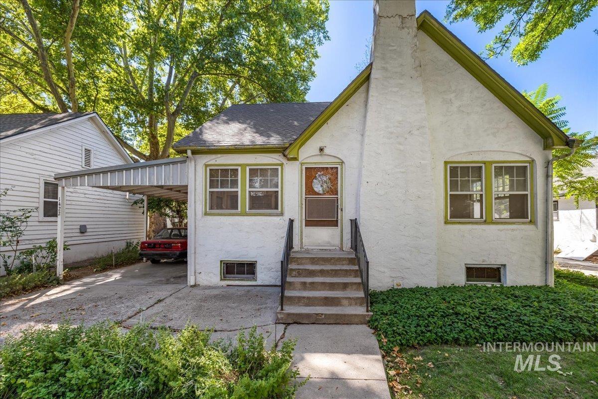 View of front of property featuring stucco siding, a shingled roof, and a carport