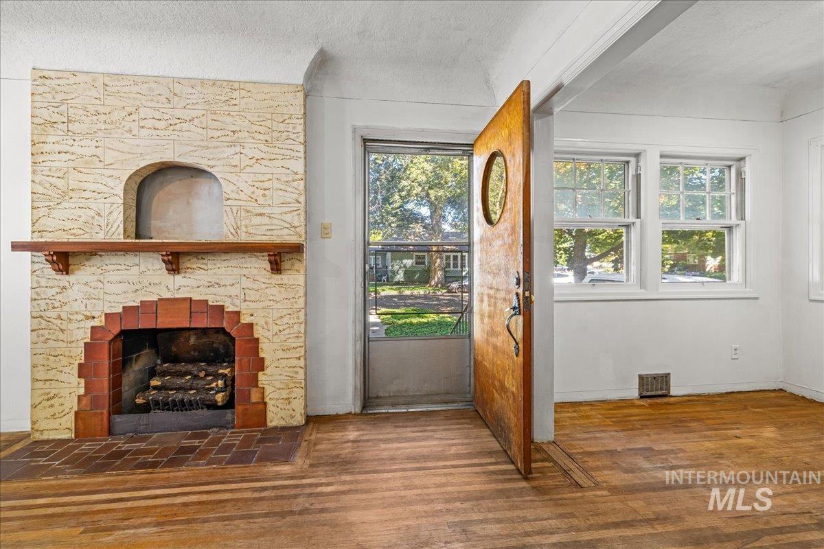 Unfurnished living room featuring wood finished floors, a textured ceiling, and a fireplace
