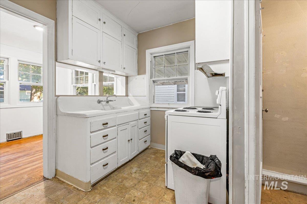 Kitchen featuring white cabinets, electric range, and healthy amount of natural light