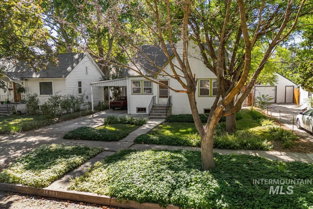 View of front of house with stucco siding, driveway, and an attached carport
