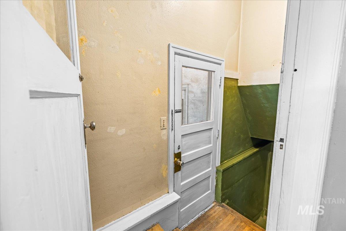 Doorway with a textured wall and wood finished floors