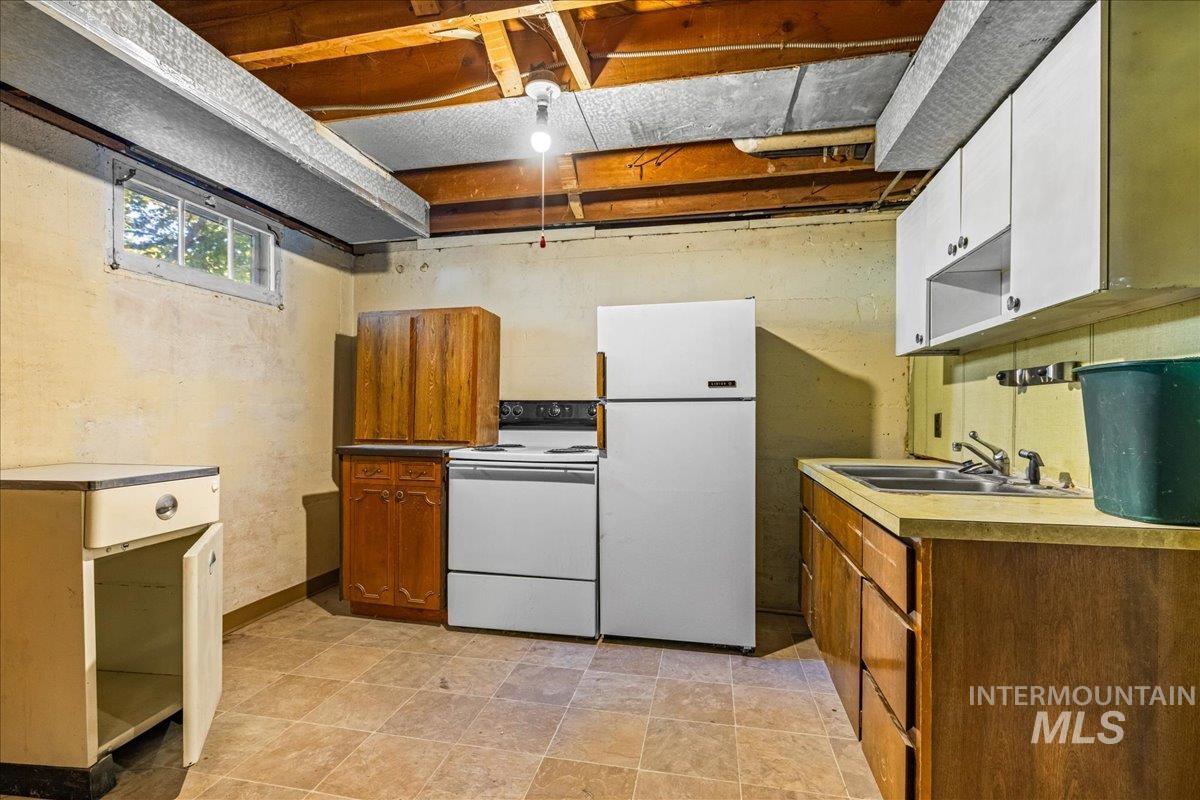 Kitchen featuring white appliances, light countertops, and white cabinets