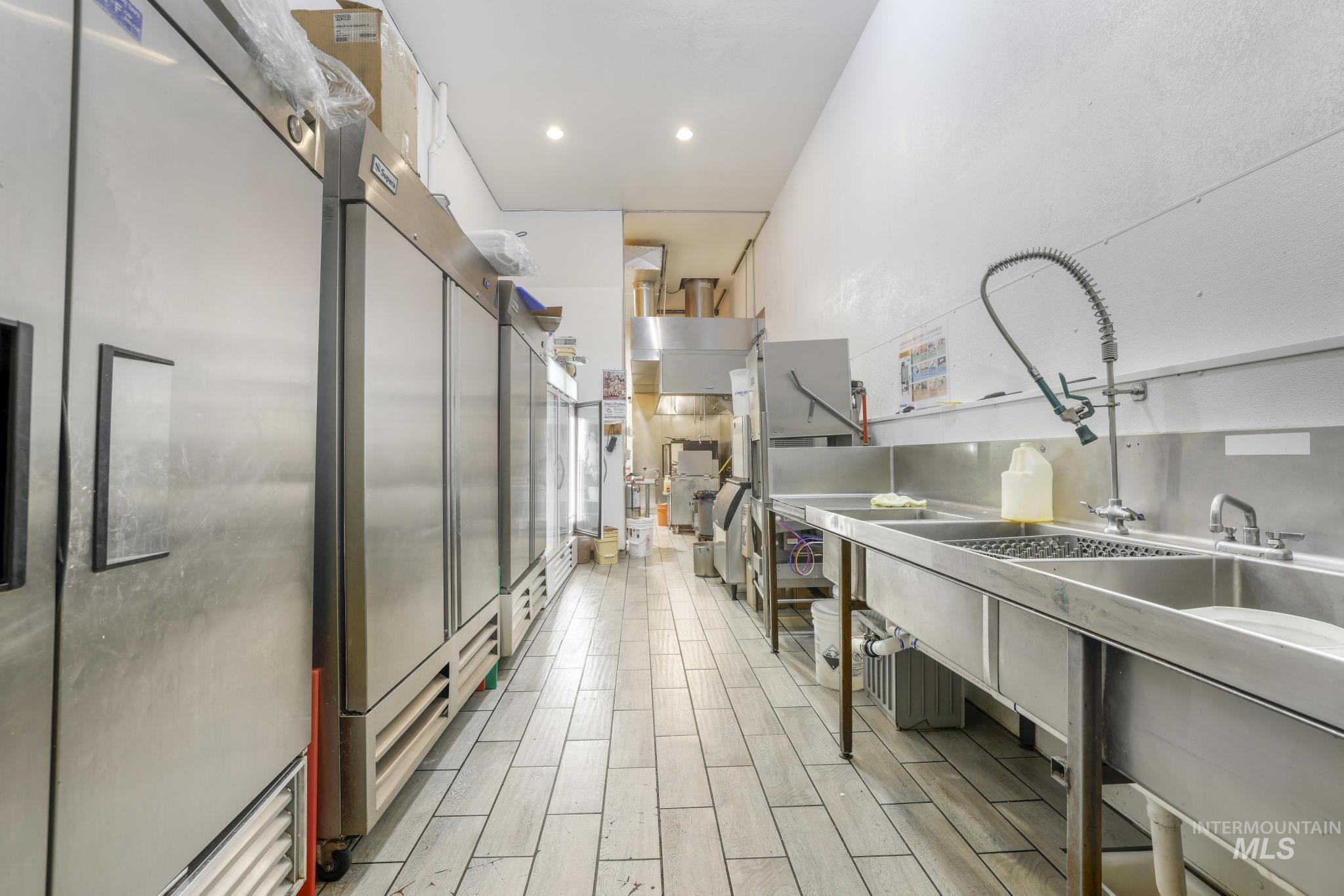 Kitchen featuring stainless steel refrigerator, high quality fridge, wood finish floors, stainless steel countertops, and recessed lighting