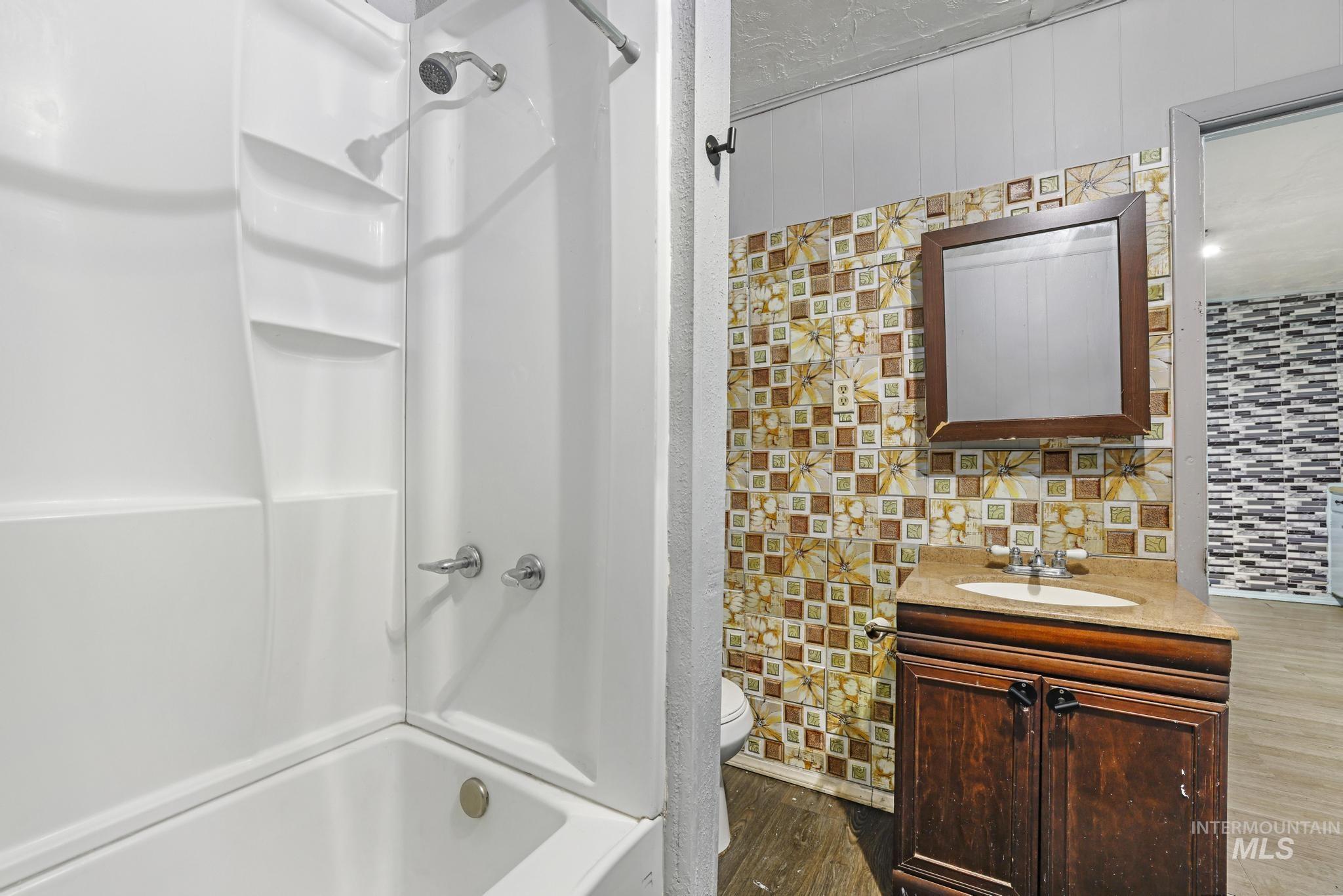 Full bathroom with shower / bathtub combination, vanity, dark wood-type flooring, a textured ceiling, and backsplash