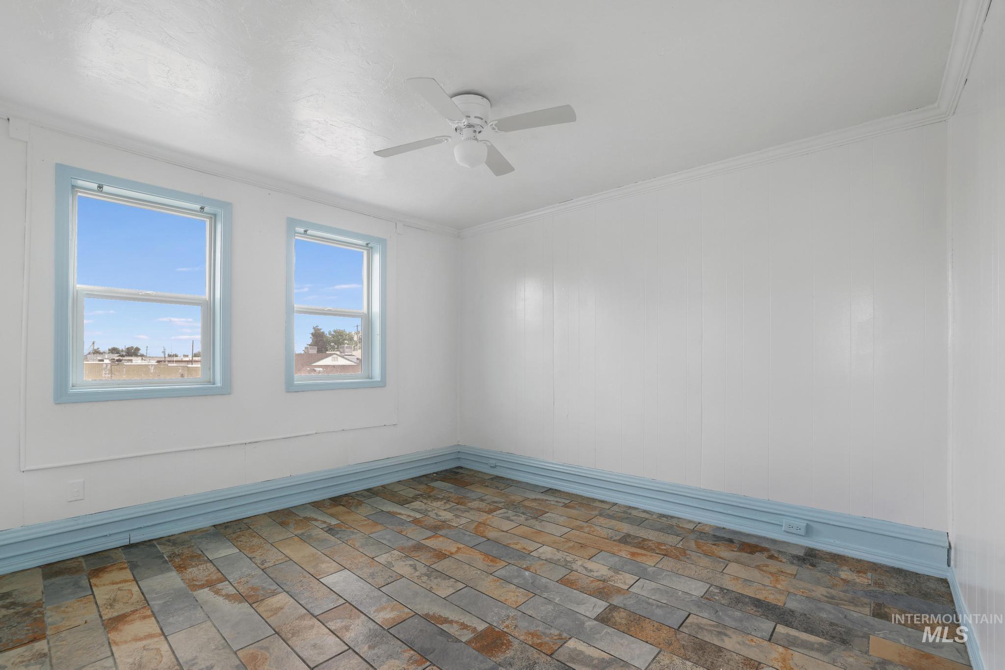 Empty room featuring ceiling fan and crown molding