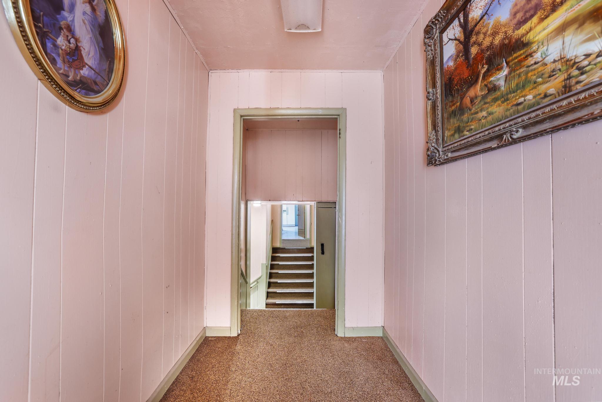 Hallway with carpet and wood walls