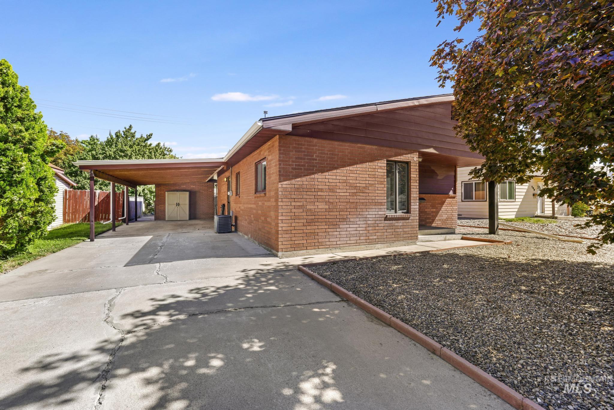 View of home's exterior with driveway, an attached carport, and brick siding