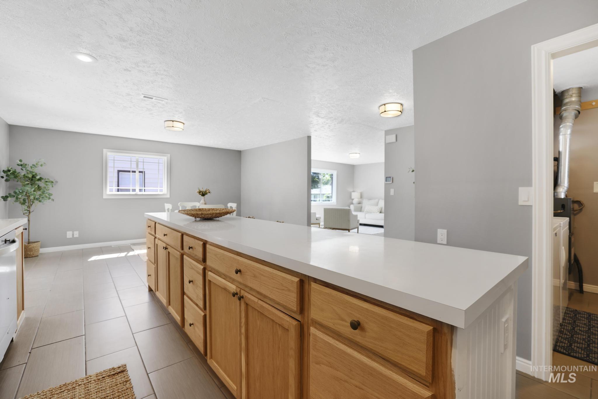 Kitchen with light countertops, light tile patterned flooring, a textured ceiling, and dishwashing machine