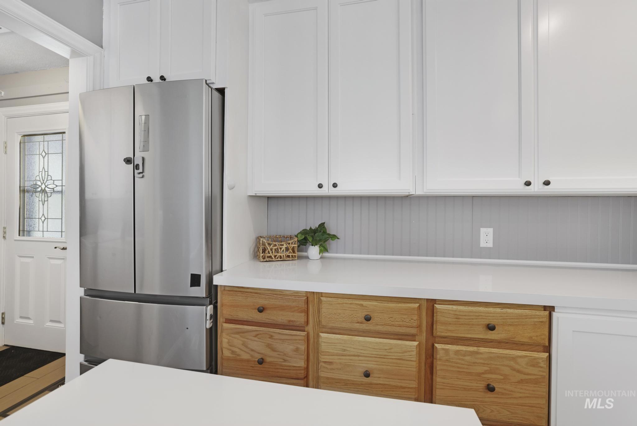 Kitchen with freestanding refrigerator, white cabinetry, and light countertops