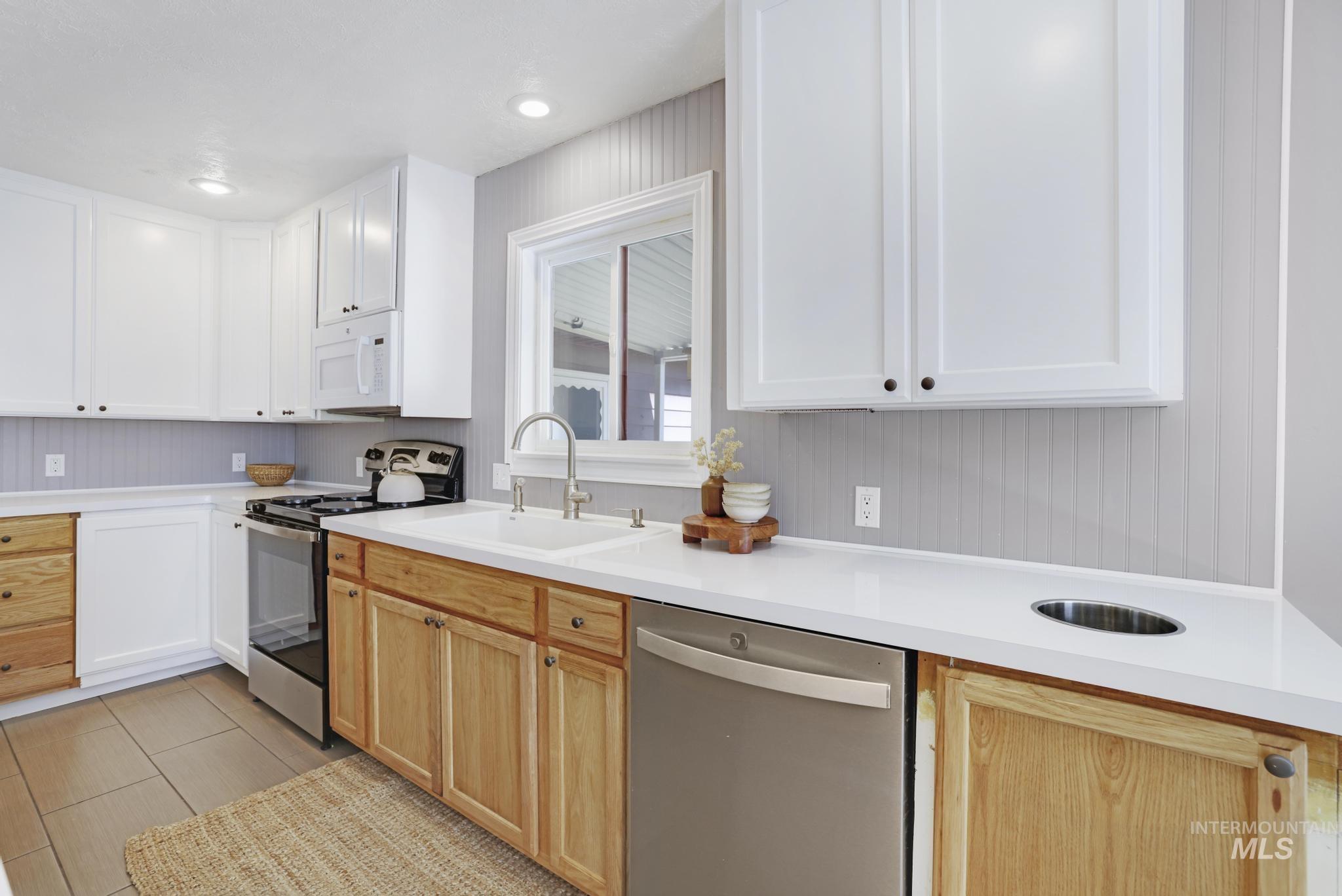 Kitchen featuring light countertops, appliances with stainless steel finishes, white cabinetry, and recessed lighting