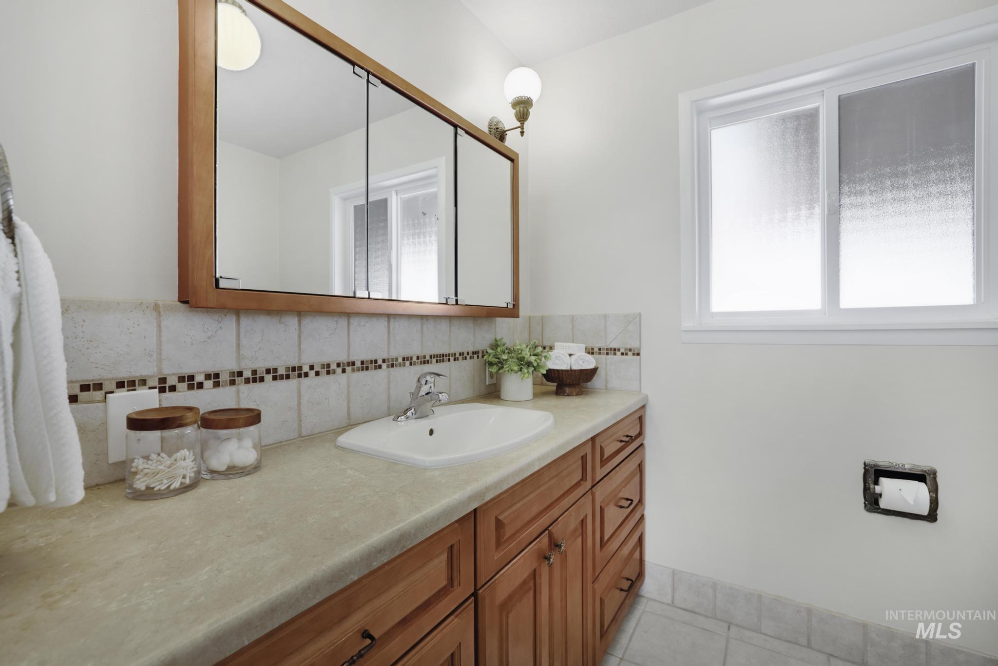 Bathroom with vanity, light tile patterned floors, and tasteful backsplash