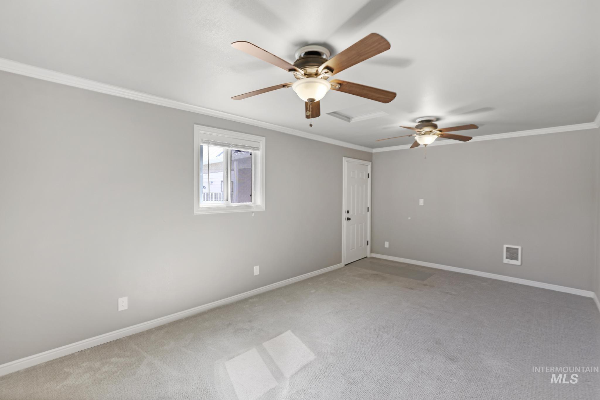 Carpeted spare room featuring ornamental molding and ceiling fan