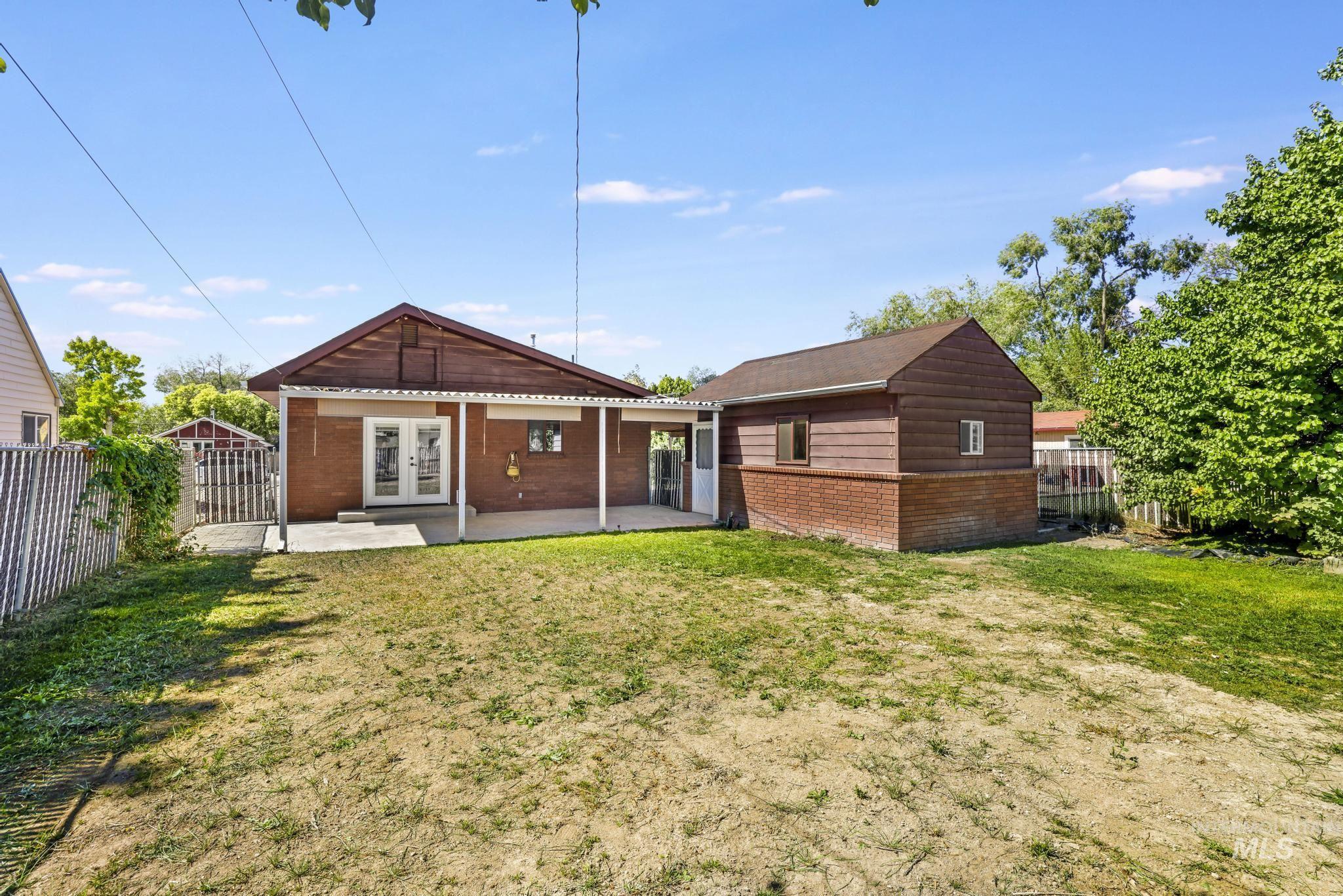 Rear view of house featuring a fenced backyard, a patio, french doors, and brick siding