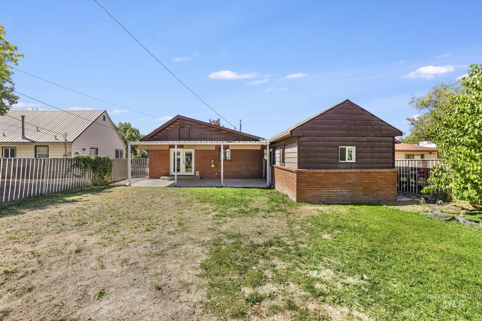 Rear view of property with a patio area, a fenced backyard, brick siding, and french doors