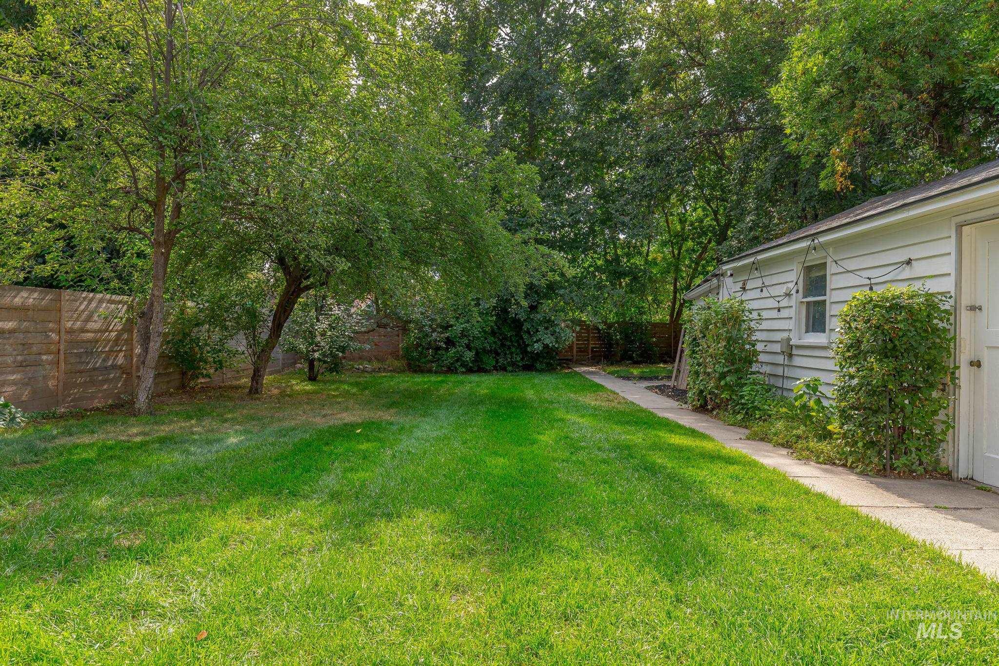 Fenced backyard featuring view of scattered trees