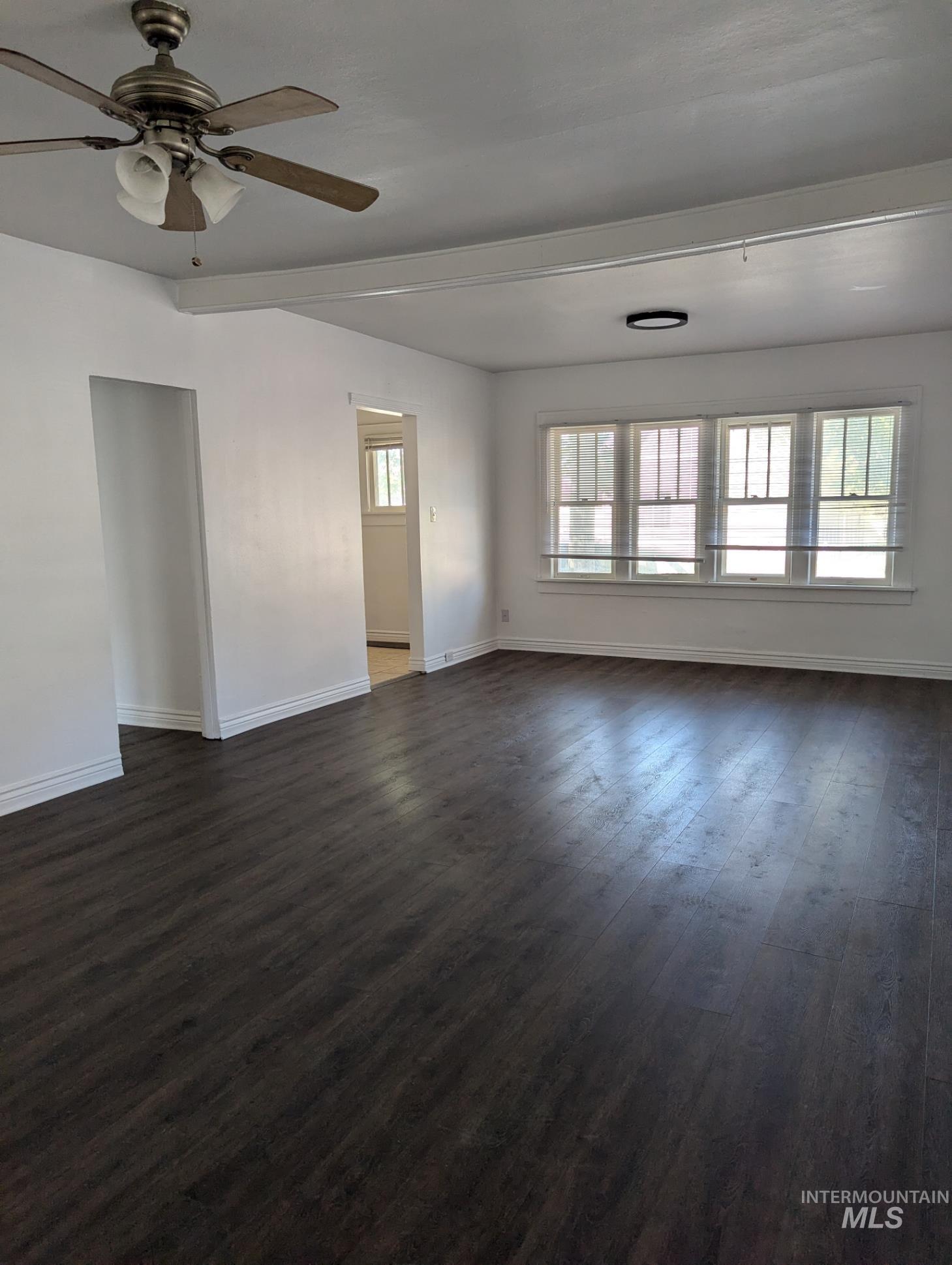 Spare room with dark wood-style flooring, healthy amount of natural light, and a ceiling fan