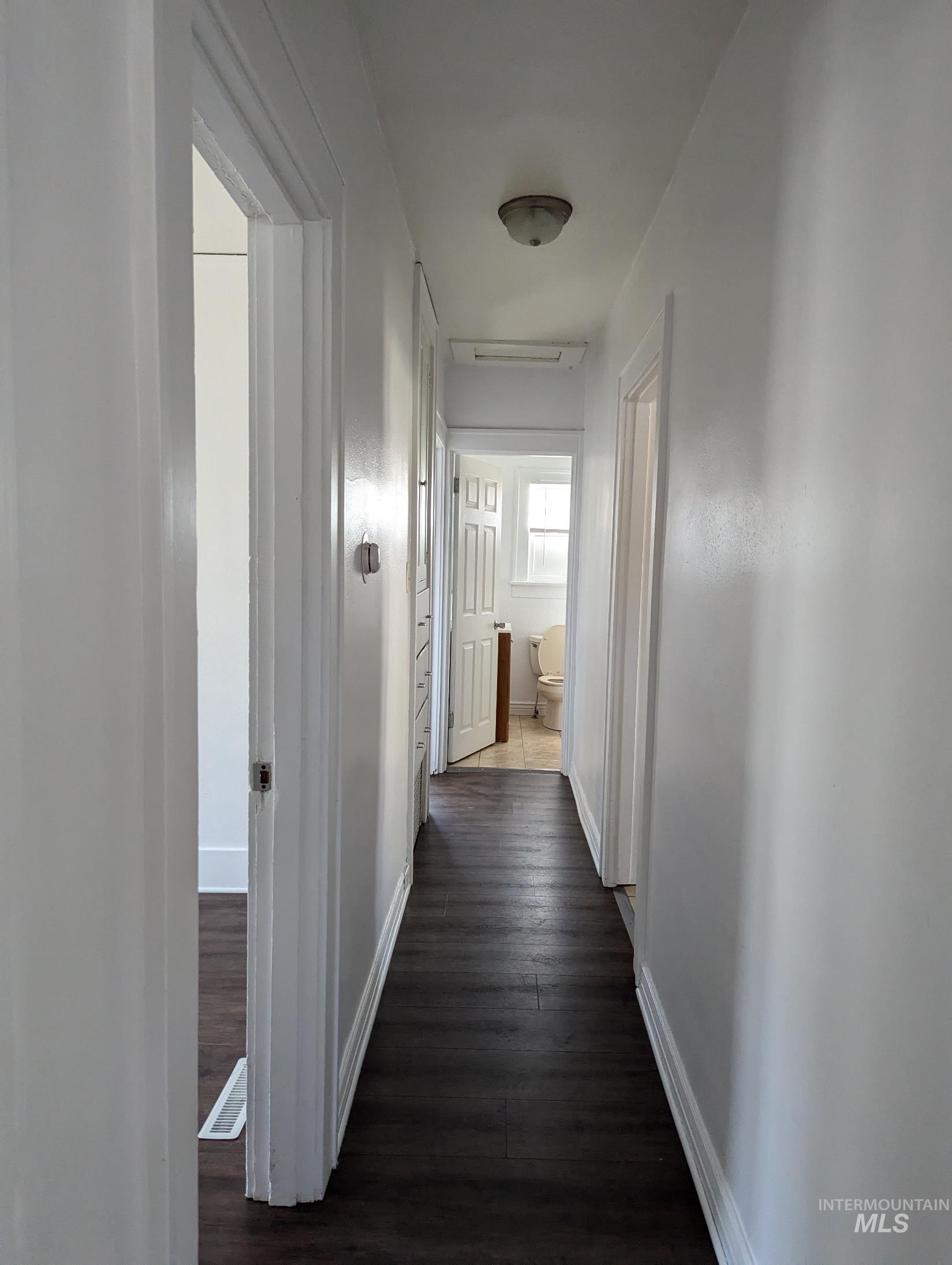 Corridor with dark wood-style floors and baseboards