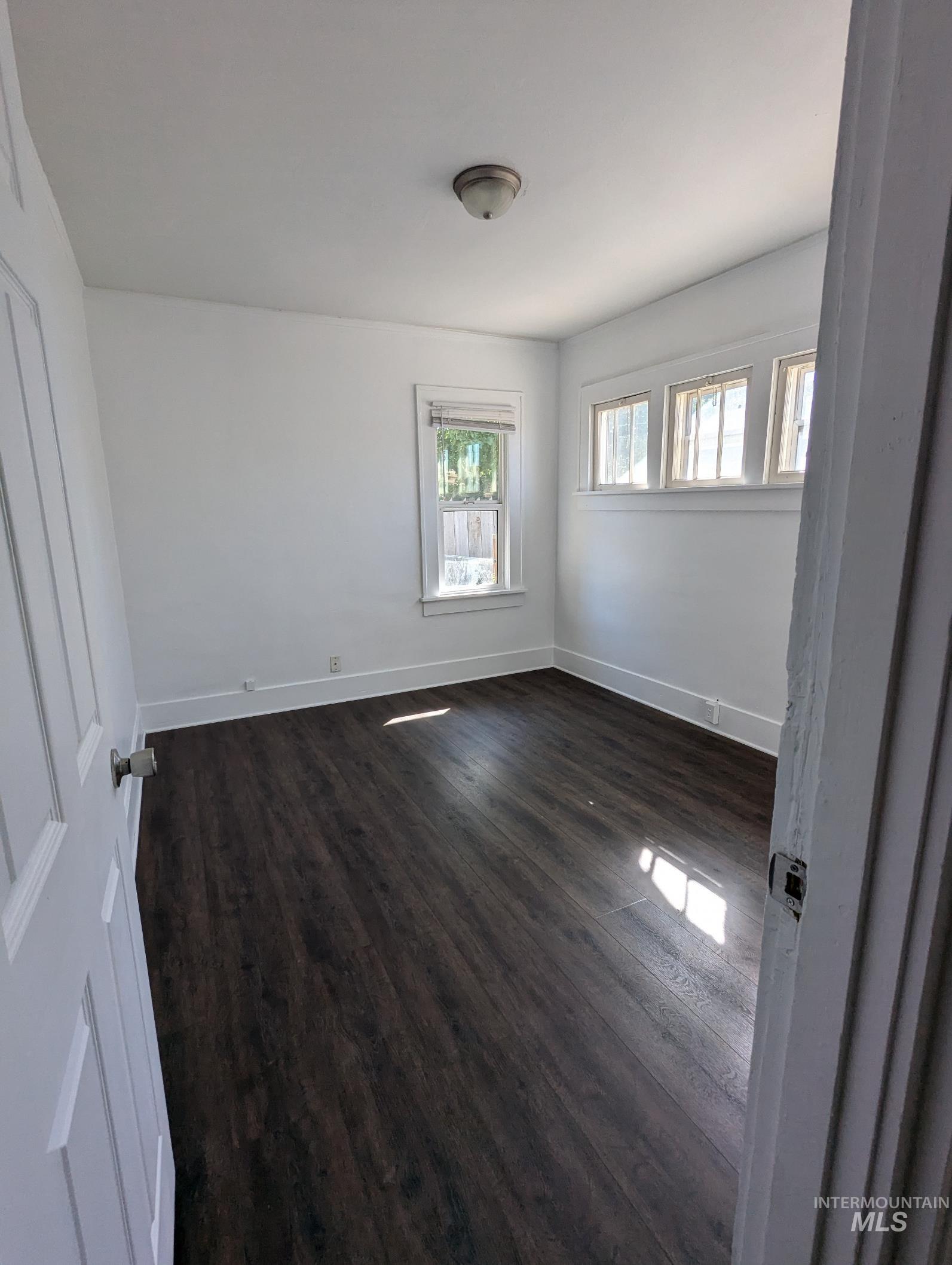 Unfurnished room featuring plenty of natural light and dark wood finished floors