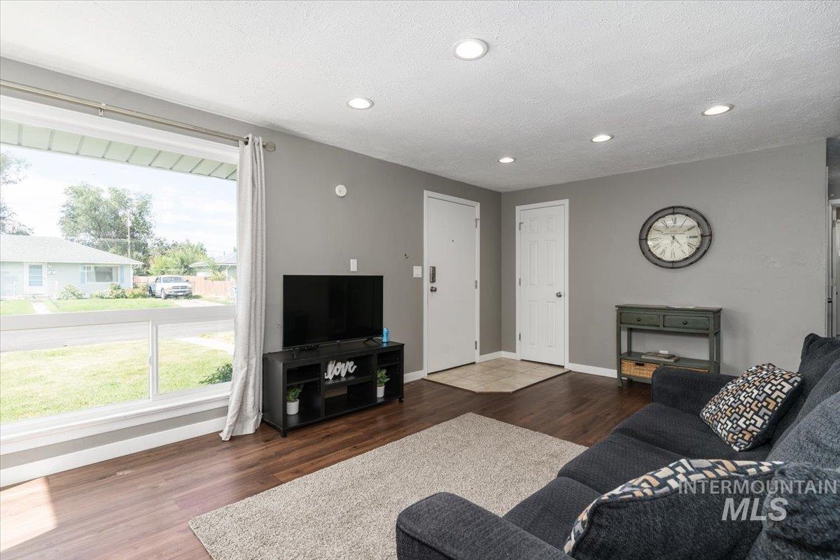 Living room with dark wood-type flooring, recessed lighting, and a textured ceiling