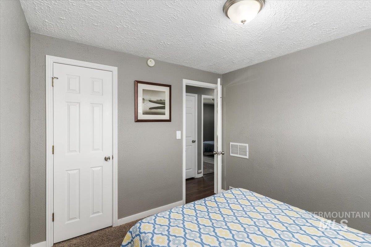 Bedroom featuring dark carpet, a textured ceiling, and a textured wall