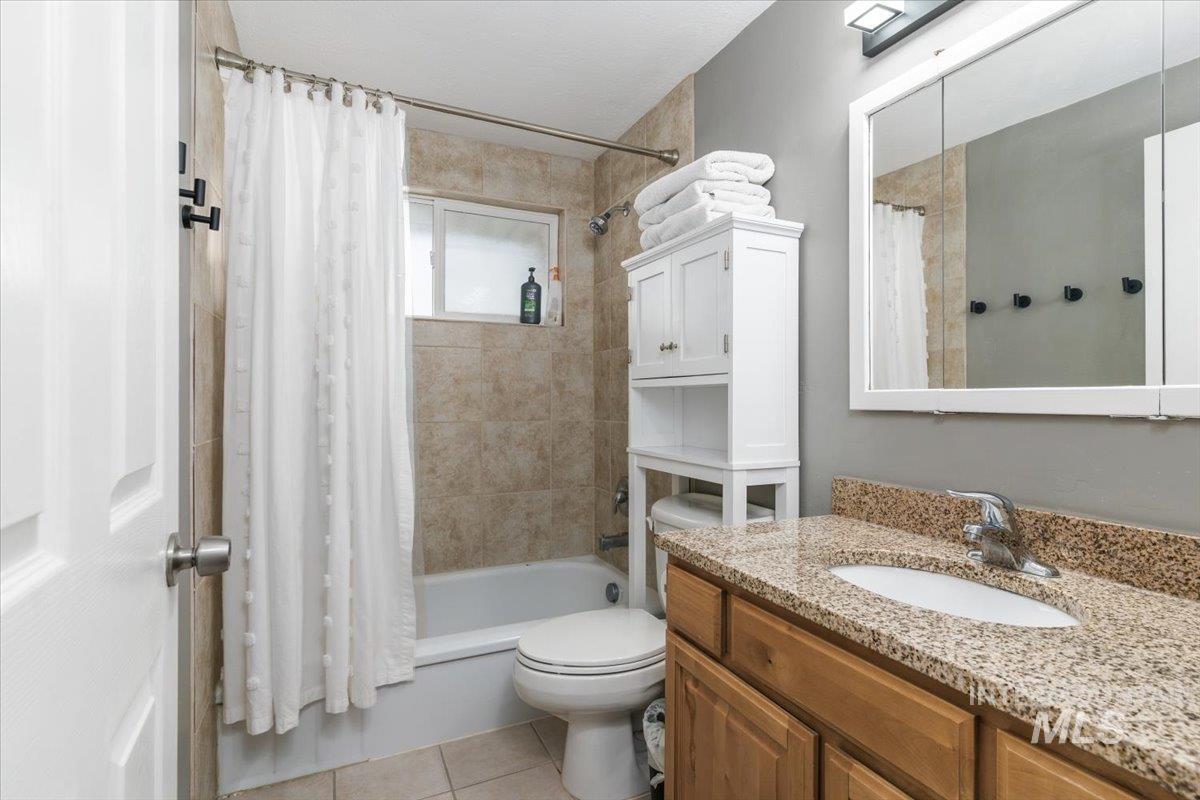 Bathroom with shower / bath combo with shower curtain, vanity, and light tile patterned flooring