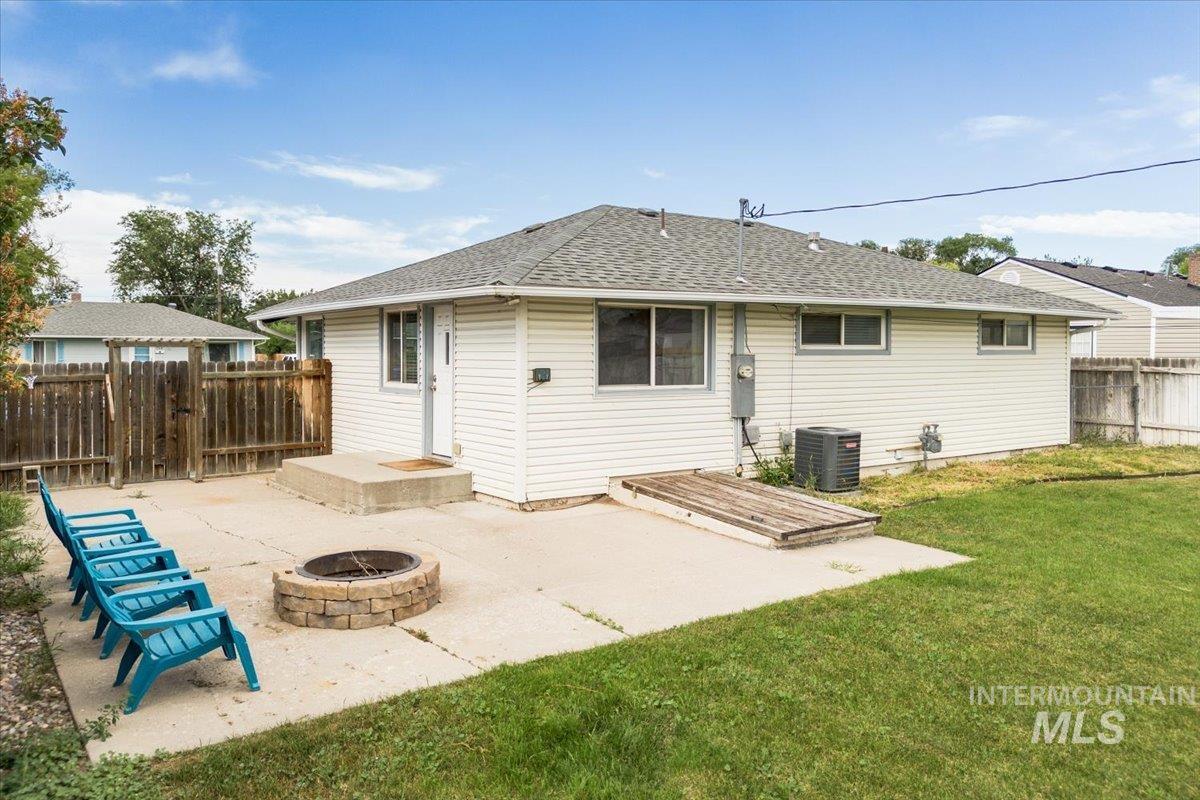 Rear view of property with a patio area, a shingled roof, and an outdoor fire pit