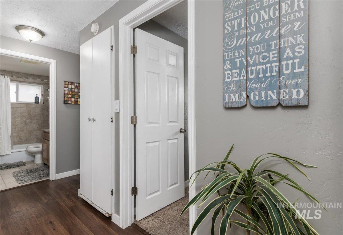 Hall with a textured ceiling and dark wood-type flooring