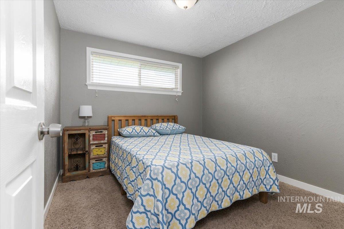Carpeted bedroom with a textured wall and a textured ceiling