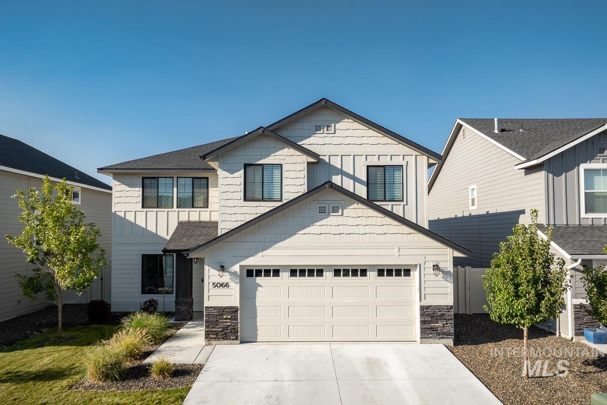 Craftsman inspired home with board and batten siding, driveway, and stone siding