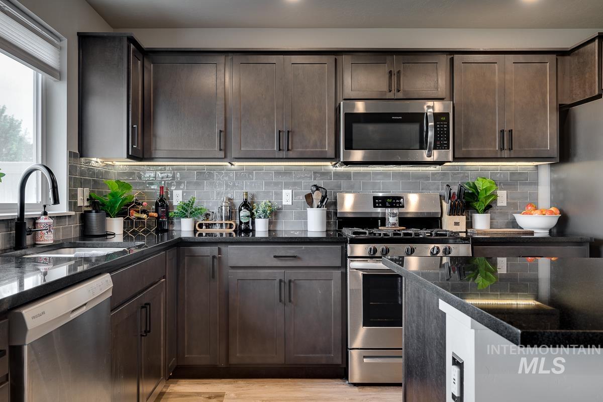 Kitchen featuring appliances with stainless steel finishes, dark brown cabinets, decorative backsplash, and recessed lighting