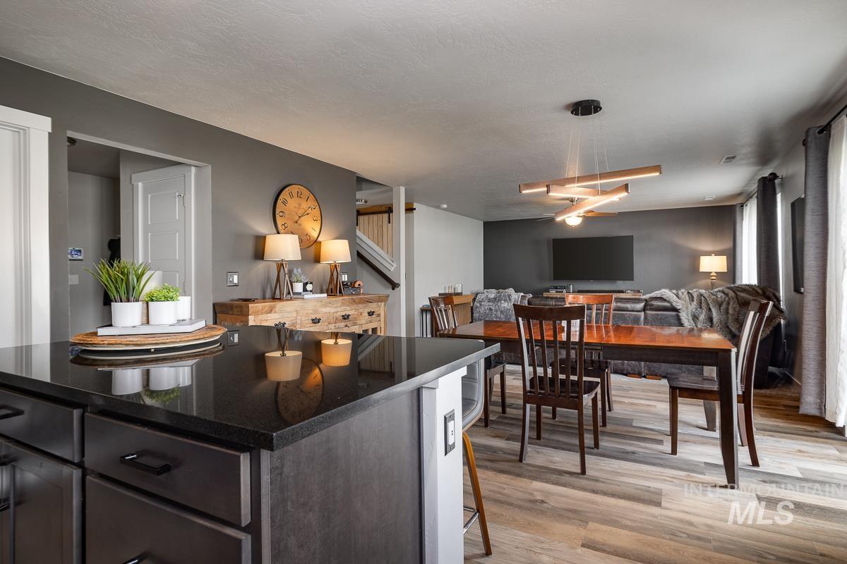 Kitchen featuring dark stone counters, light wood-style floors, a kitchen island, open floor plan, and a kitchen breakfast bar