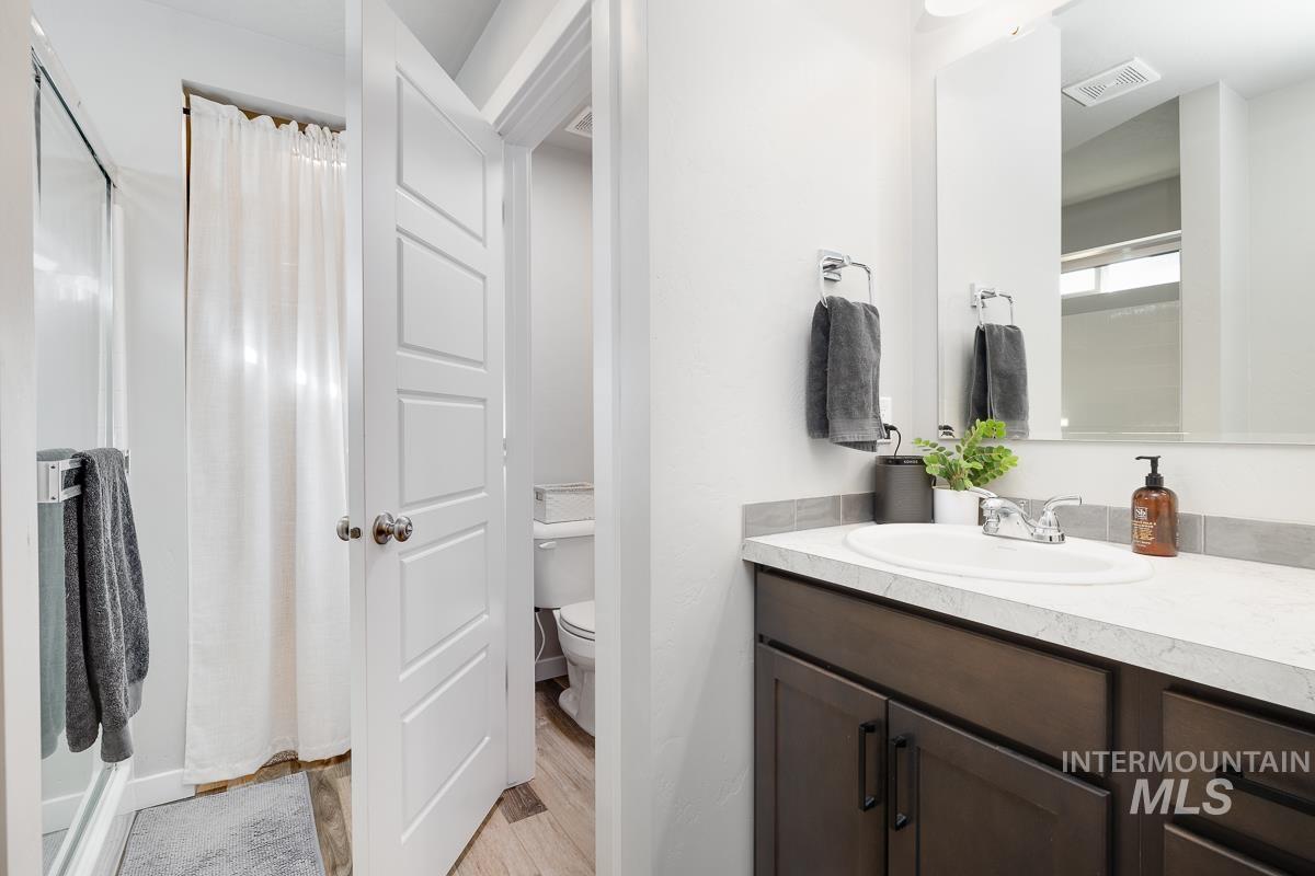 Bathroom with vanity, a stall shower, and light wood finished floors