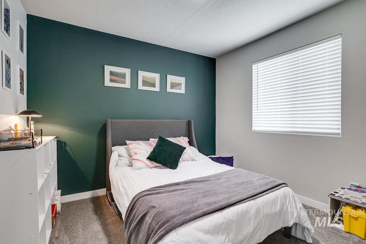 Bedroom featuring baseboards and dark carpet