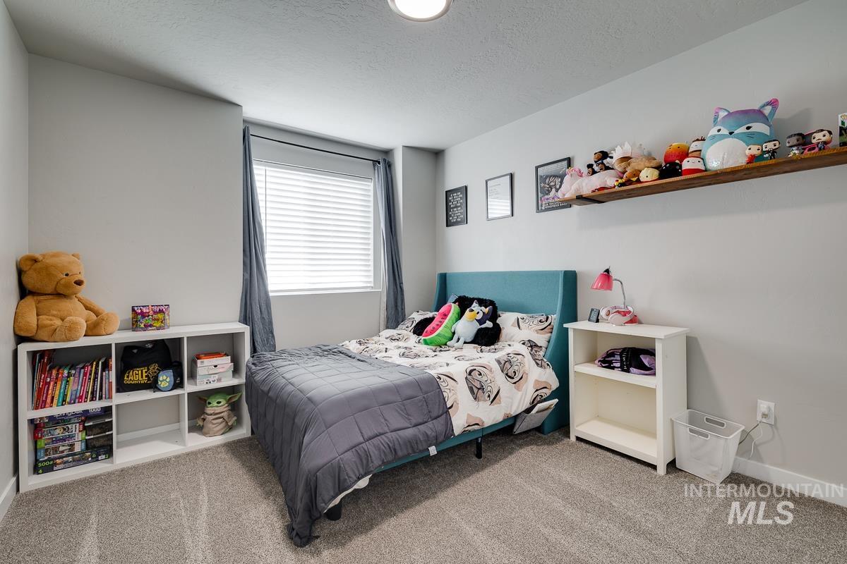 Carpeted bedroom with a textured ceiling and baseboards