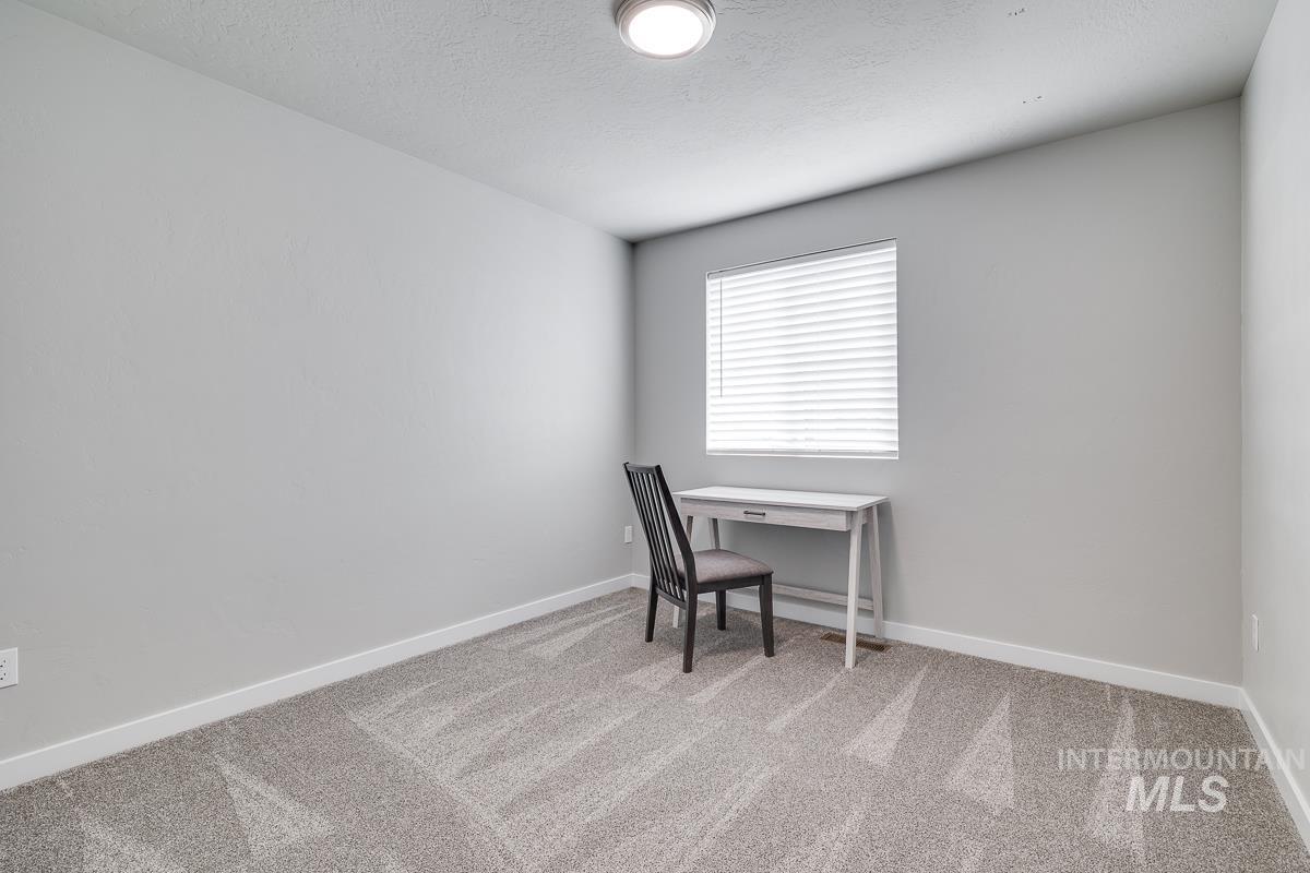 Office with light carpet and a textured ceiling