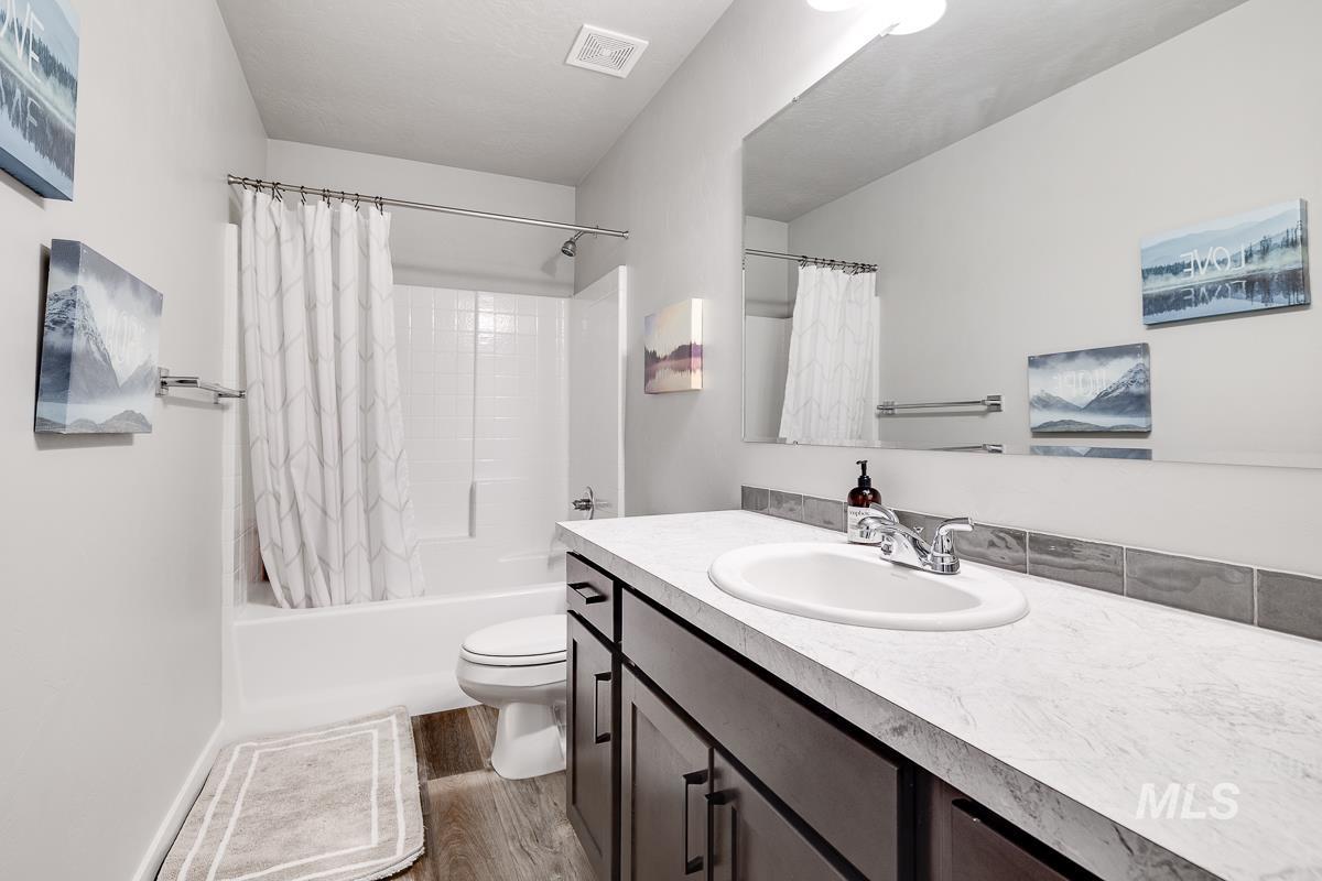 Full bathroom featuring shower / bath combo with shower curtain, light wood-style floors, and vanity