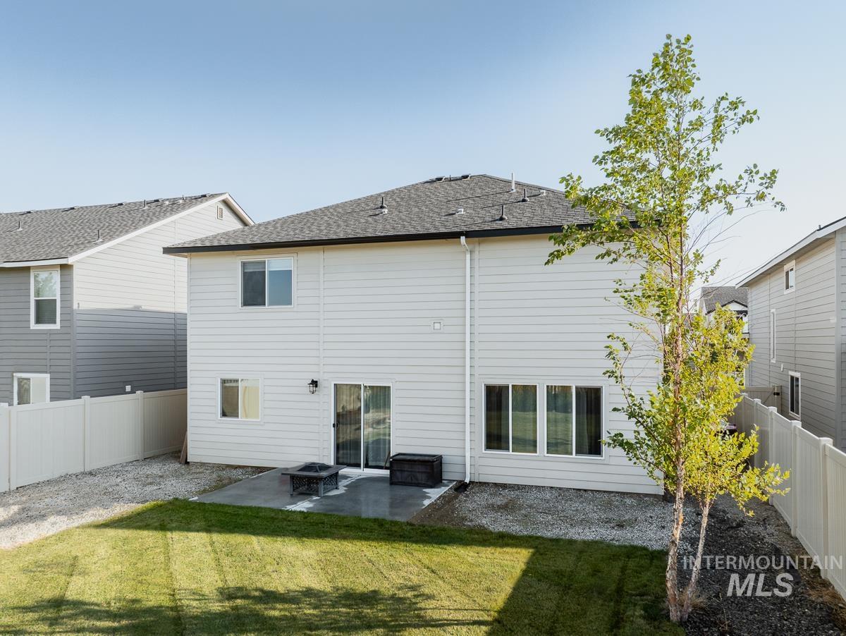 Back of property with a patio, a fenced backyard, a shingled roof, and a fire pit