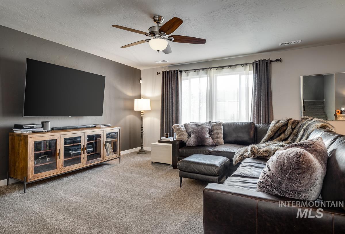 Carpeted living room with a textured ceiling and a ceiling fan