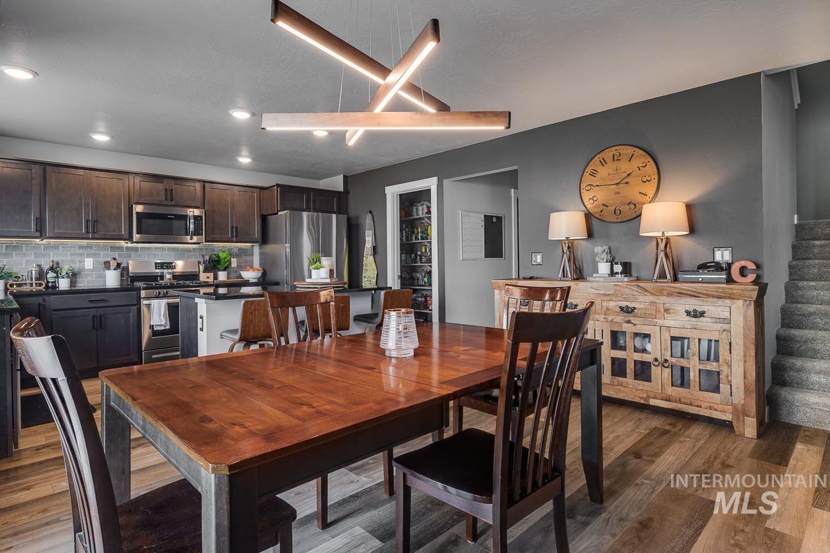 Dining area with wood finished floors, stairway, and recessed lighting