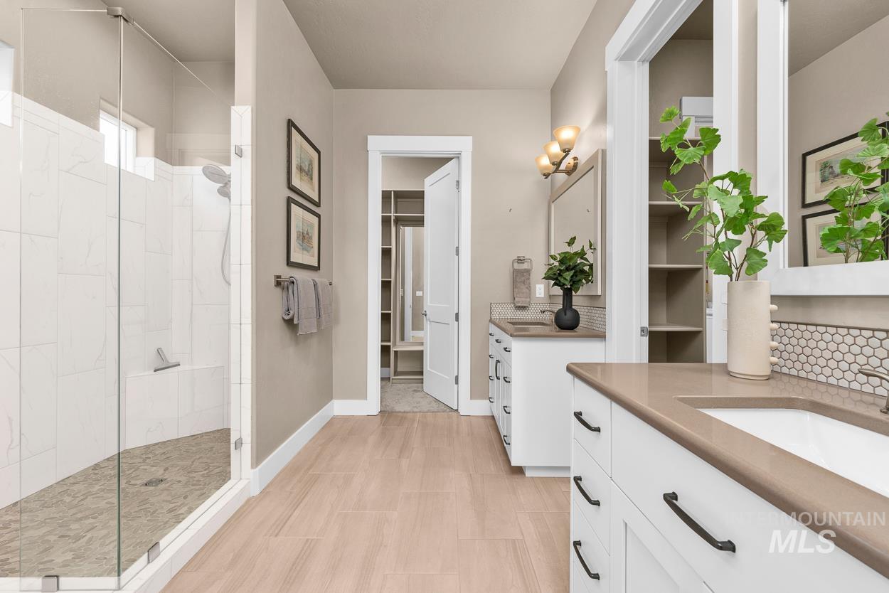 Bathroom featuring walk in shower, two vanities, decorative backsplash, and a walk in closet