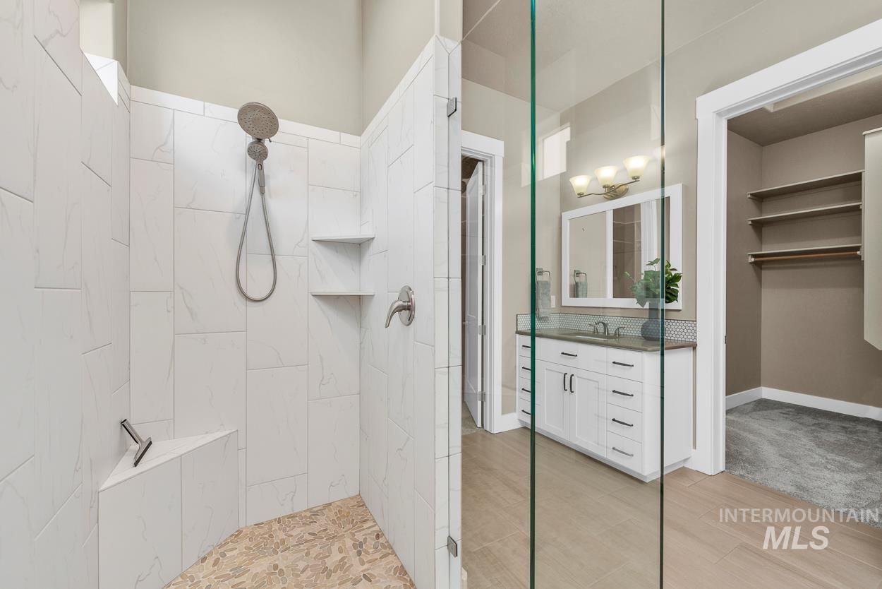 Full bath featuring a walk in shower, vanity, and light wood-style flooring
