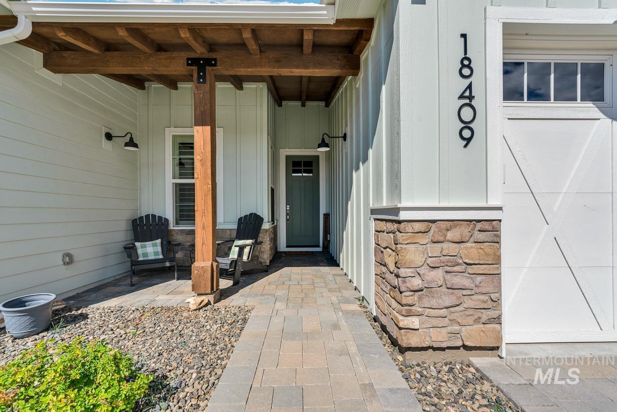 Property entrance with stone siding, a porch, and board and batten siding