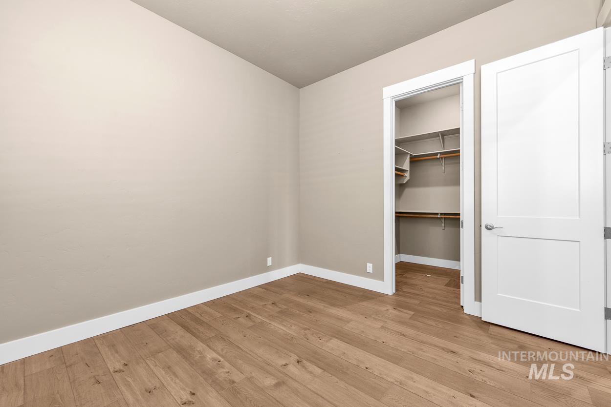 Unfurnished bedroom with a walk in closet and light wood-style flooring